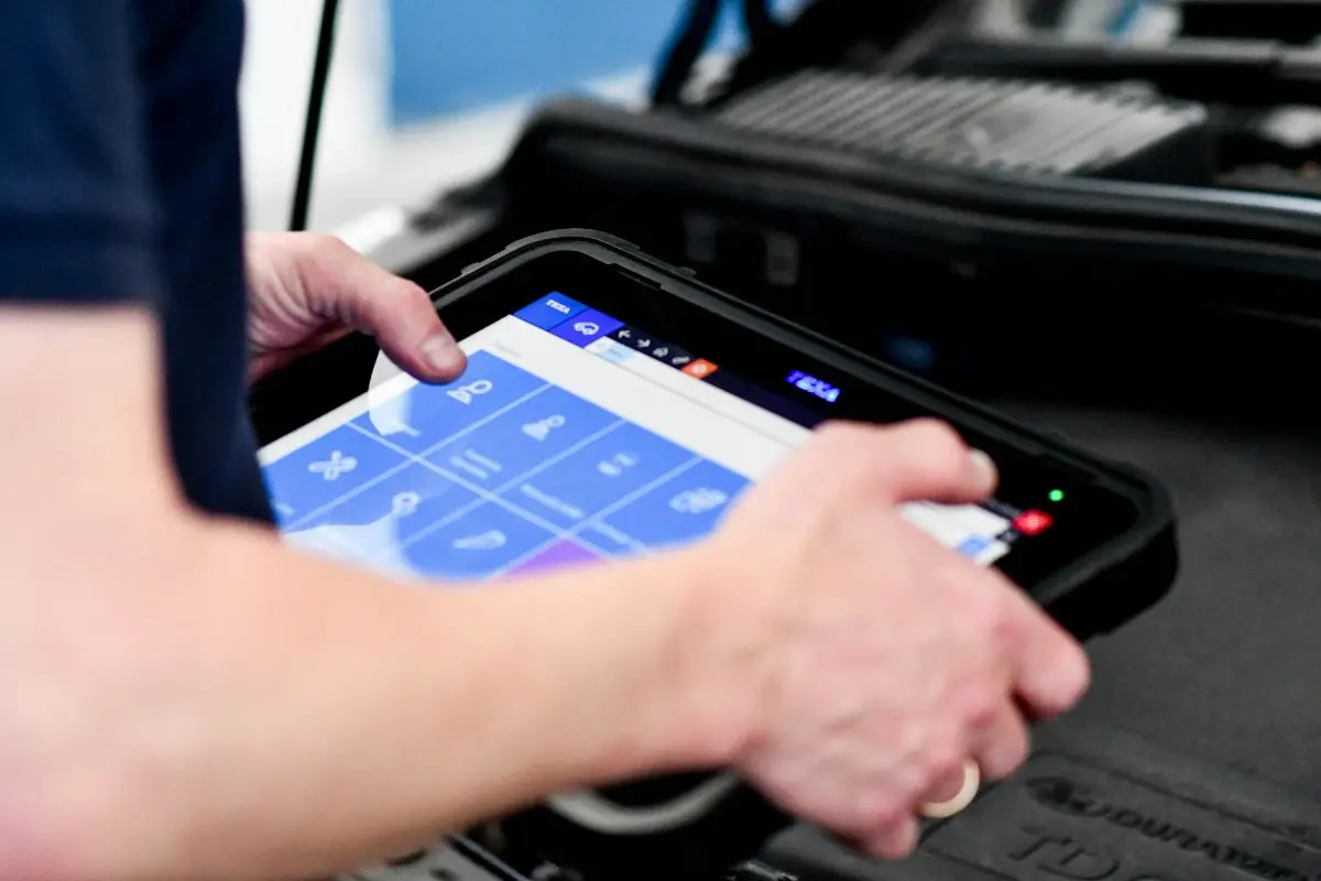 Technician reading a diagnostic scan tablet at the car