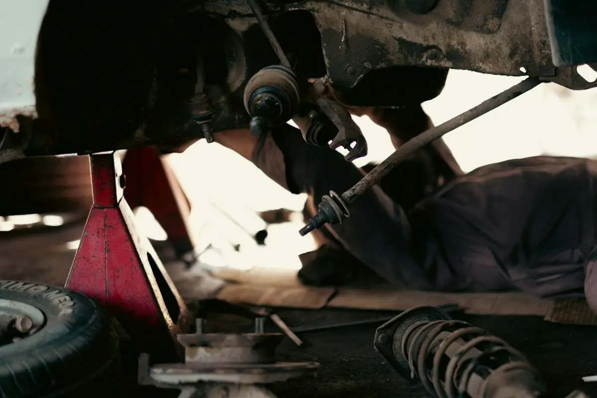 Mechanic working on suspension parts under a car on stands